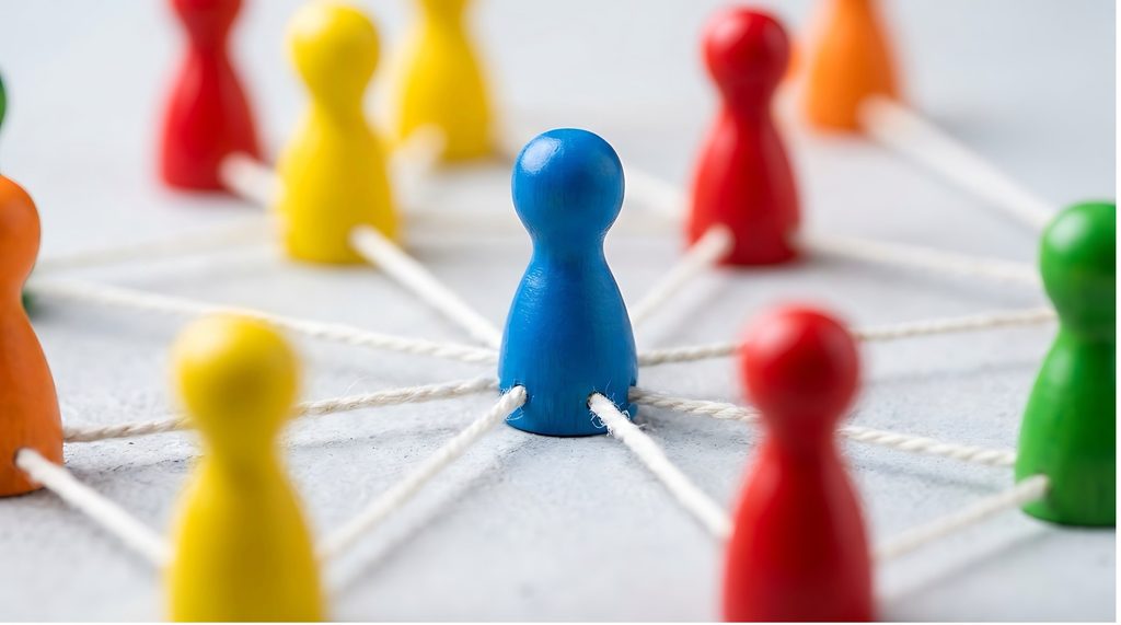 Colourful wooden figures connected by white string, with a blue figure in focus at the centre.